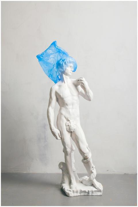 A classical nude sculpture adorned with a blue pla