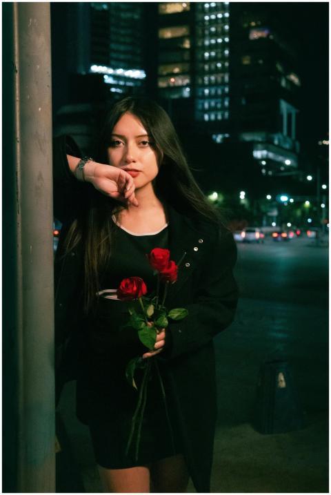 A woman holds red roses on a vibrant night in Ciud