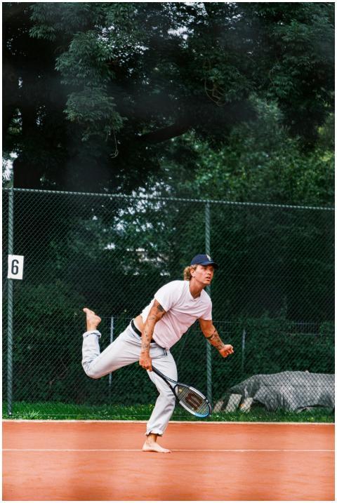 Dynamic shot of a barefoot man playing tennis on a