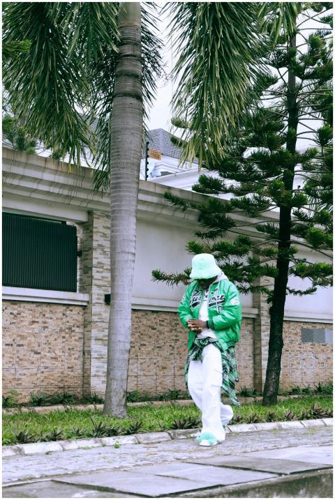 Stylish man in green jacket and hat walking by pal
