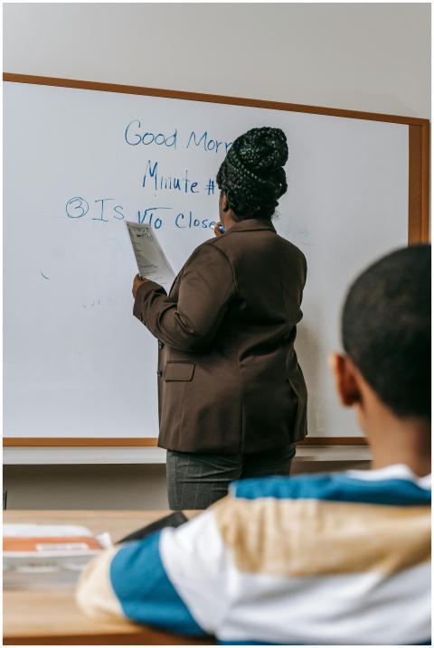 A teacher writes on a whiteboard during a classroo
