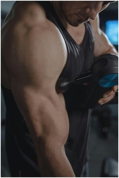 Close-up of a muscular arm being massaged with a h