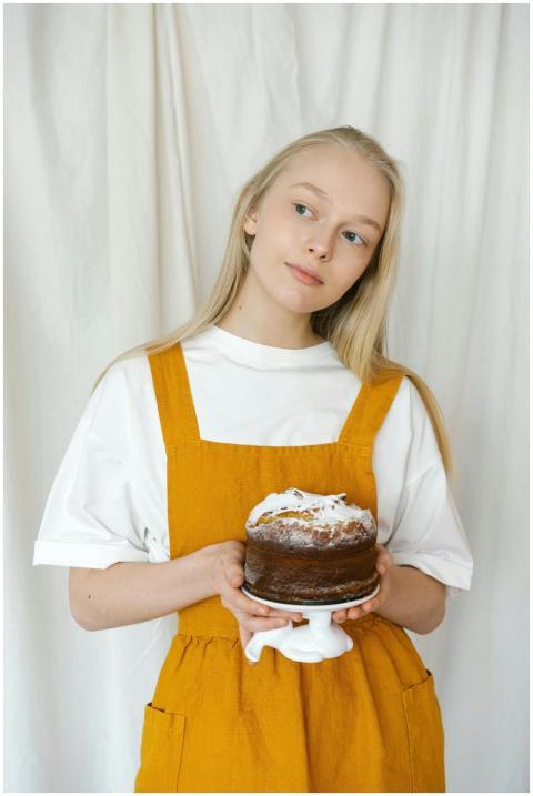A young girl with blonde hair holds a homemade cak