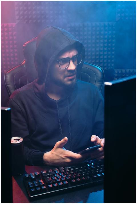 Man with hoodie using computer and smartphone in m