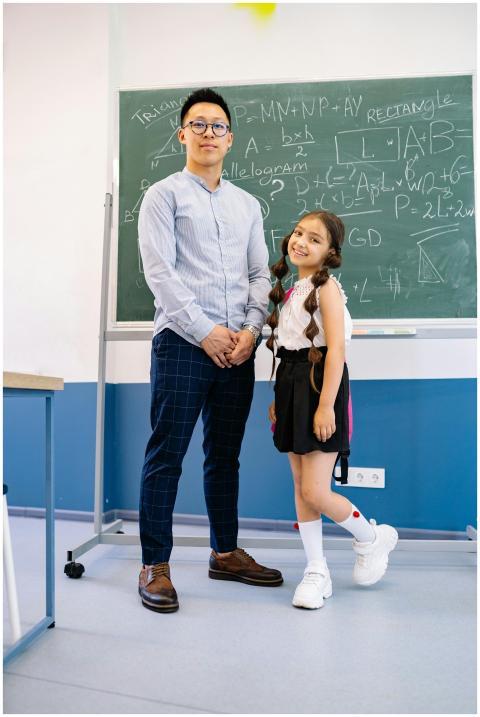 Man and young girl posing in front of a chalkboard