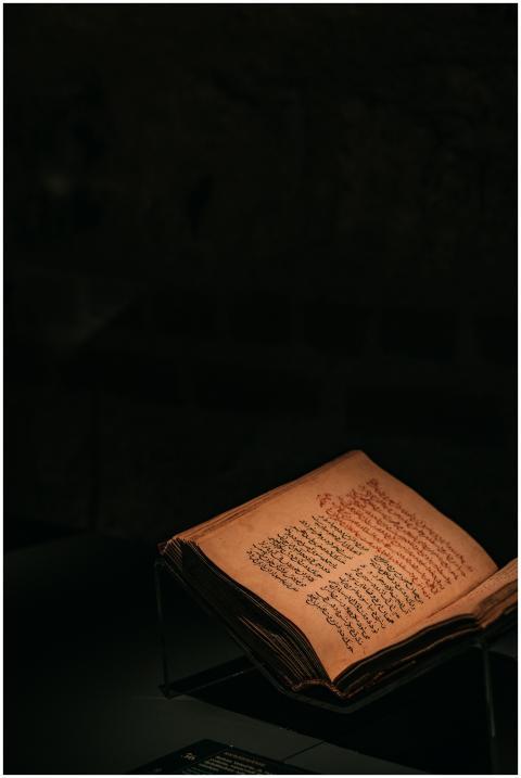 A historic open book displayed under dim lighting,