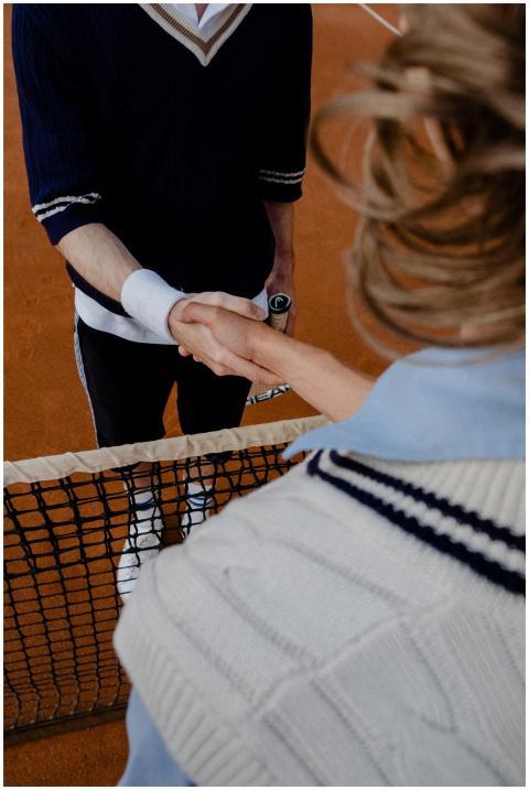 Two tennis players exchange a handshake over the n