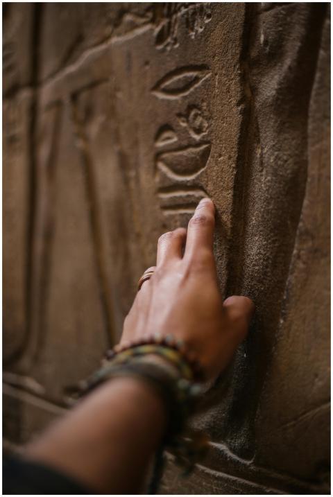 Close-up of a hand touching ancient hieroglyphics