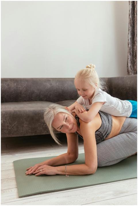 Senior woman and young girl enjoying yoga on mat a