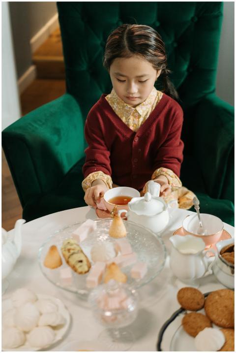A young girl savoring tea with an assortment of sw