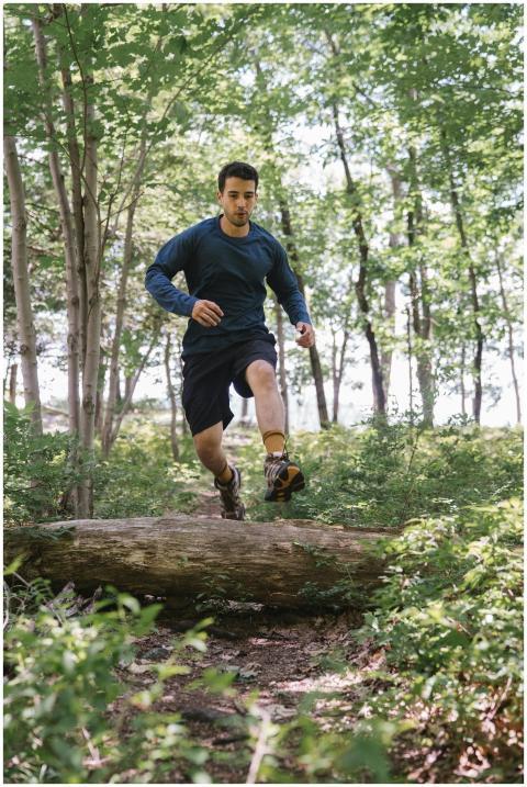 Athletic man jumping over a log during a vibrant f