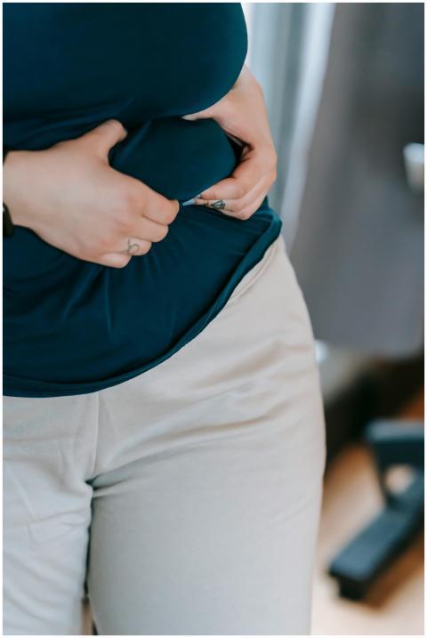 Crop anonymous plus size female touching belly on