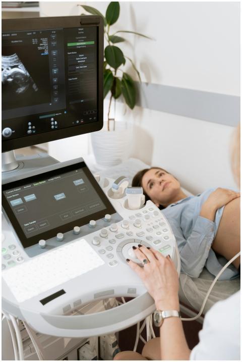 Pregnant woman undergoes ultrasound scan by medica