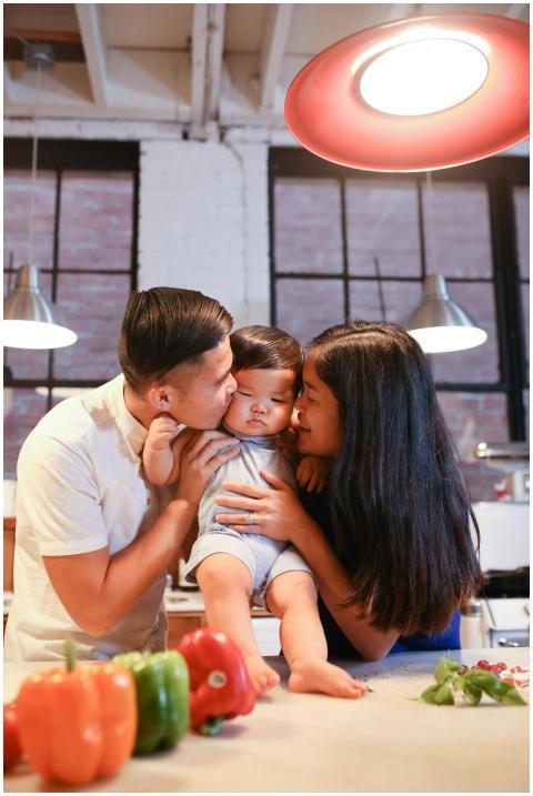 Asian parents hug their toddler in a cozy kitchen