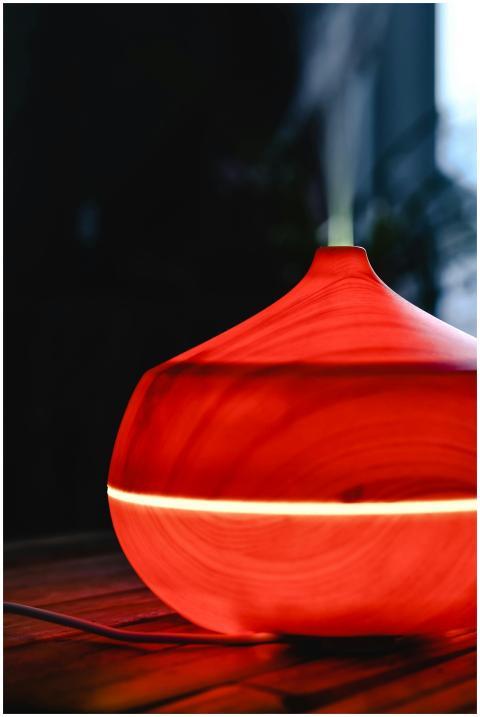 Stylish red wooden diffuser emitting gentle steam,