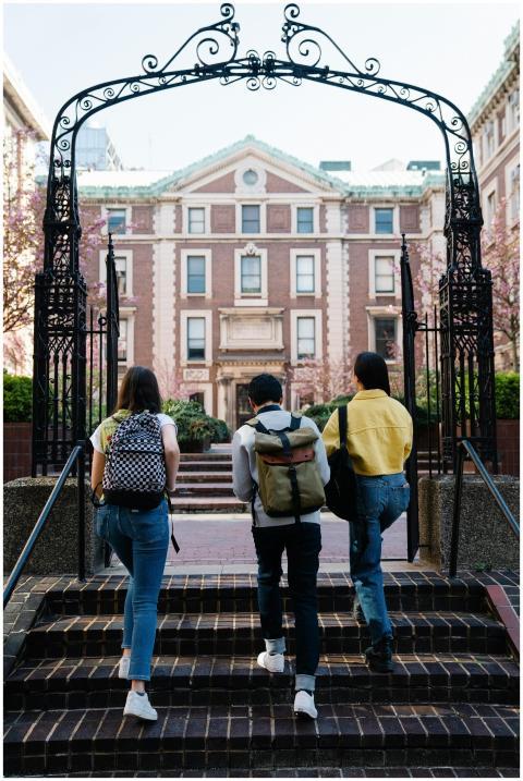 A group of students with backpacks walks towards a