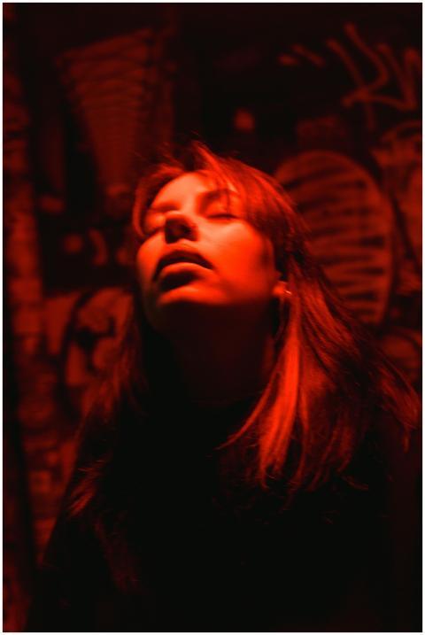 Moody portrait of a woman under red lighting again