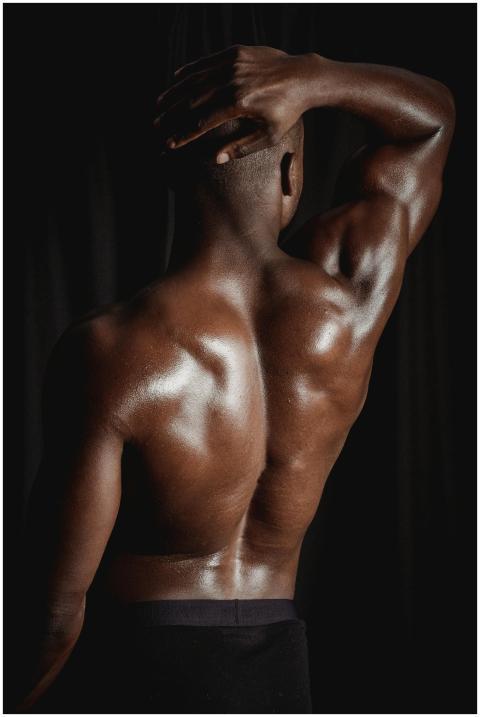 A muscular man flexes his back muscles posing shir