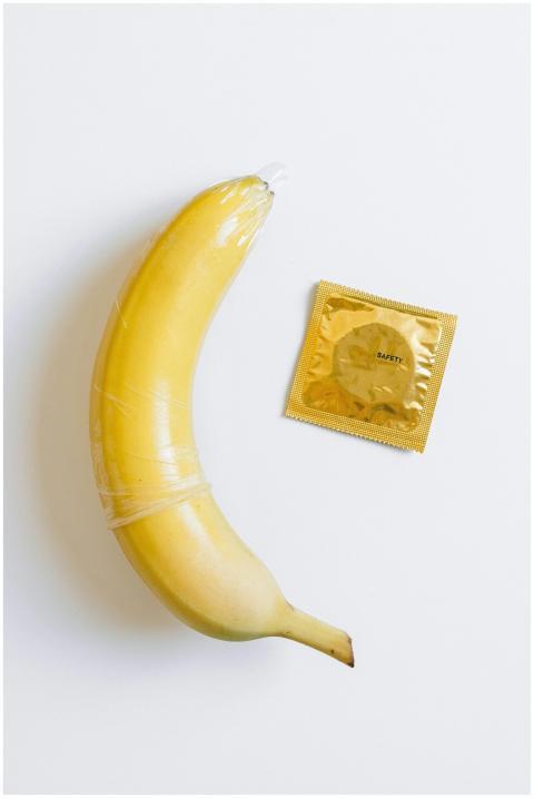 A banana wrapped in a condom next to a packaged co