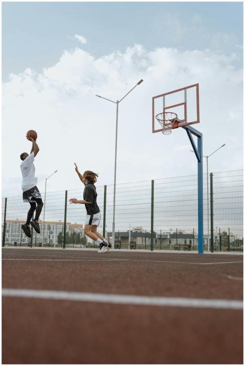 Two young men playing basketball on an outdoor cou