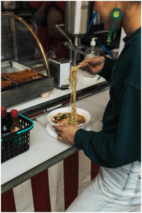 Person enjoying delicious noodles at a bustling st