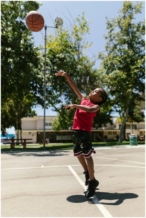A young boy energetically shoots a basketball on a