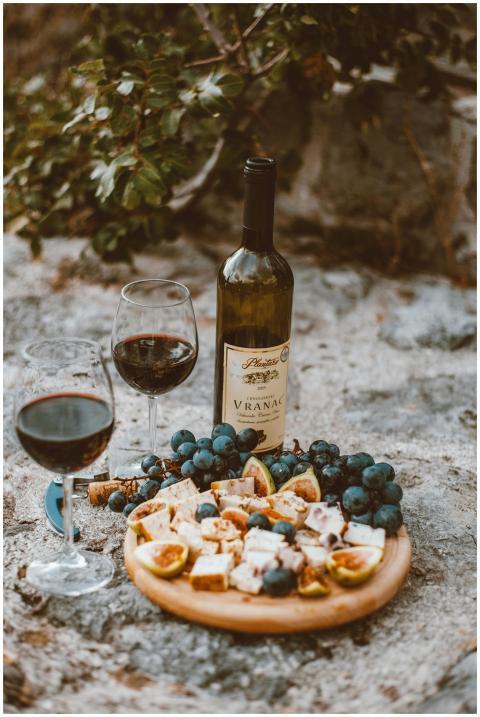 A rustic outdoor wine and cheese platter with grap