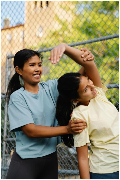 Woman guiding another in a stretching routine outd