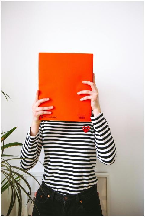 Young woman wearing a striped shirt hides face wit