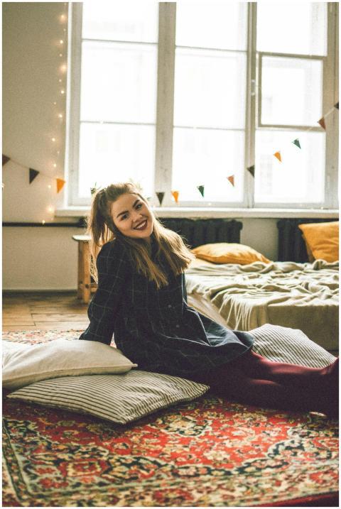 Woman with long hair sits smiling on a colorful ru