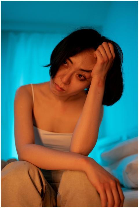 Thoughtful woman sits in soft blue light, capturin