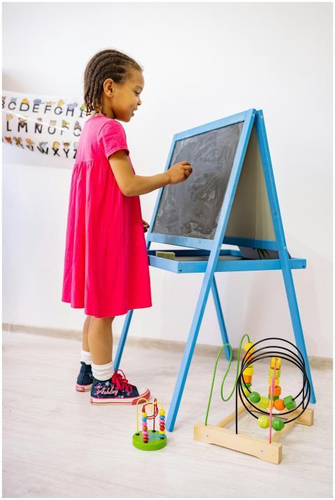 Young girl in a pink dress creatively drawing on a