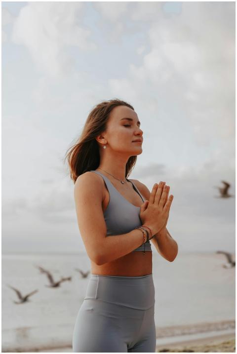 A woman in activewear meditates peacefully on a be