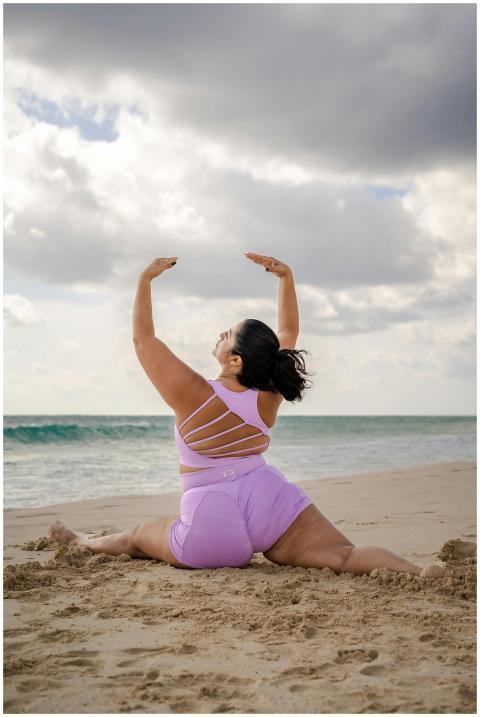 A woman performs yoga on a sandy beach, showcasing