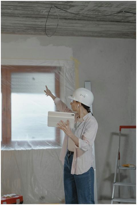 Woman in hard hat using tablet to oversee home ren