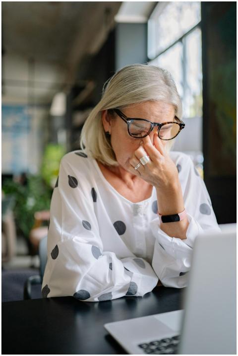 A senior woman in polka dot blouse appears stresse