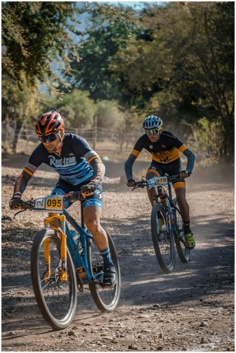 Two cyclists race fiercely on a dusty mountain tra