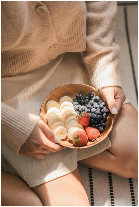 A woman holding a wooden bowl of sliced bananas, b