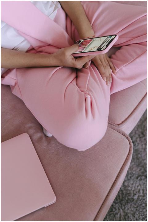 Close-up of a woman using a smartphone on a pink c