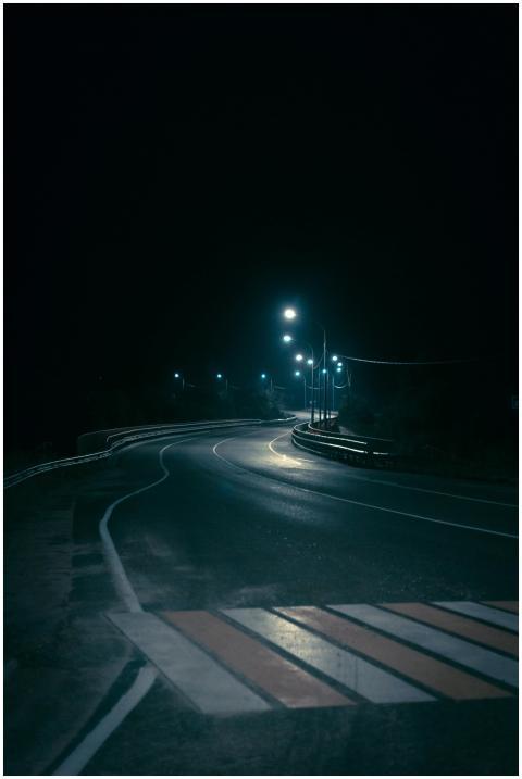 Eerie night view of a winding road lit by streetli