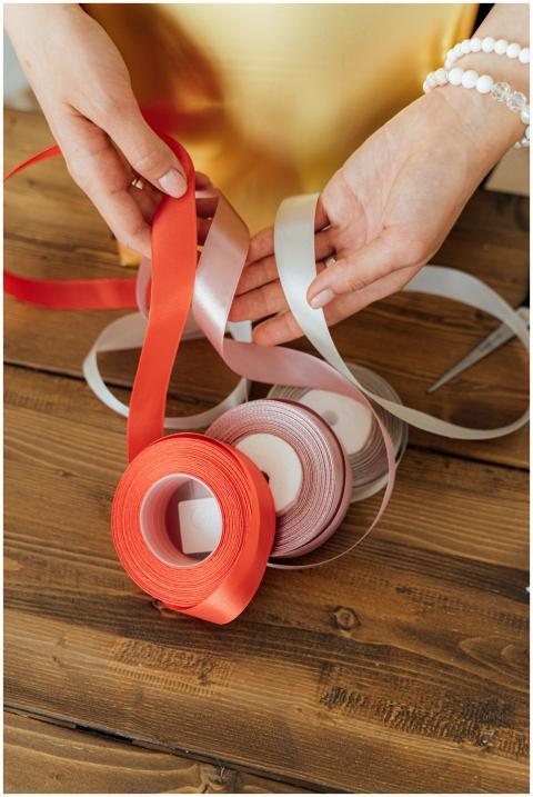 Hands arranging colorful ribbons on a wooden desk,
