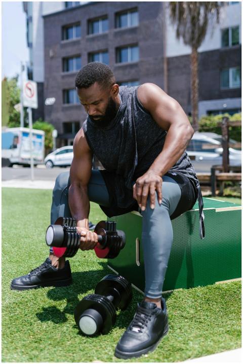 African American man lifting dumbbells outdoors, s