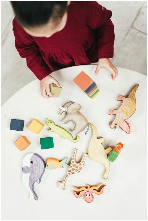 A young girl in a red dress playing with wooden an