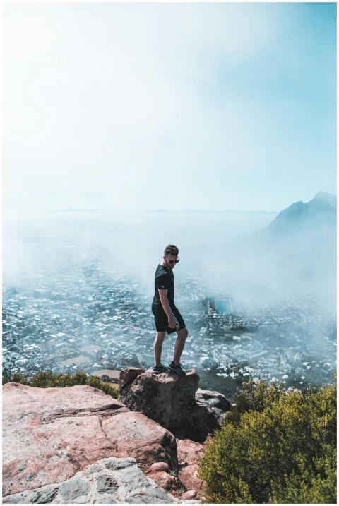 Man standing on rocky cliff with scenic view over