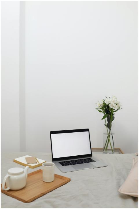 Wooden tray with tea set placed on comfortable bed