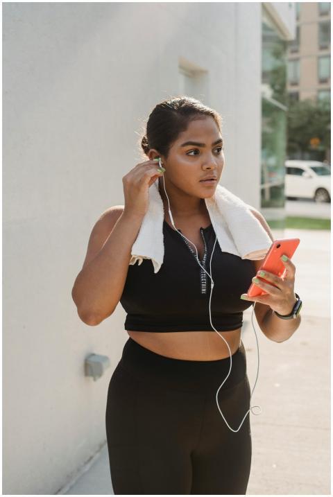 A young woman in activewear with earphones and pho