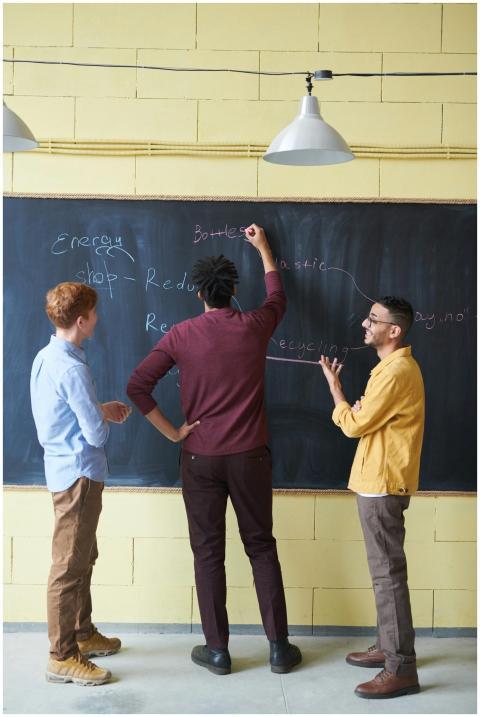 Three adults discussing strategies at a chalkboard