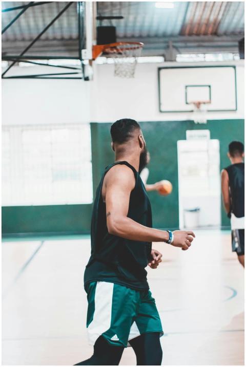 An indoor scene showing men actively playing baske
