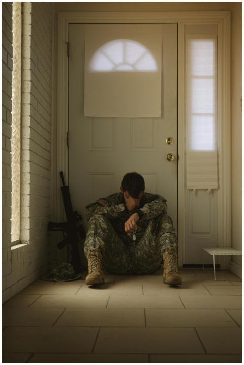 A solitary soldier in uniform sitting by a door, r