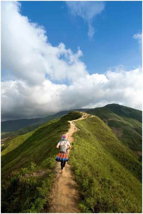 A lone hiker walking on a scenic mountain trail su